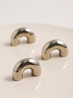 Three nickel chrome arch knobs on cream surface showing rounded arch shape