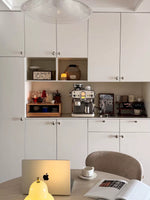 Polished chrome pebble knobs on cream kitchen cabinetry, wide shot with dining area