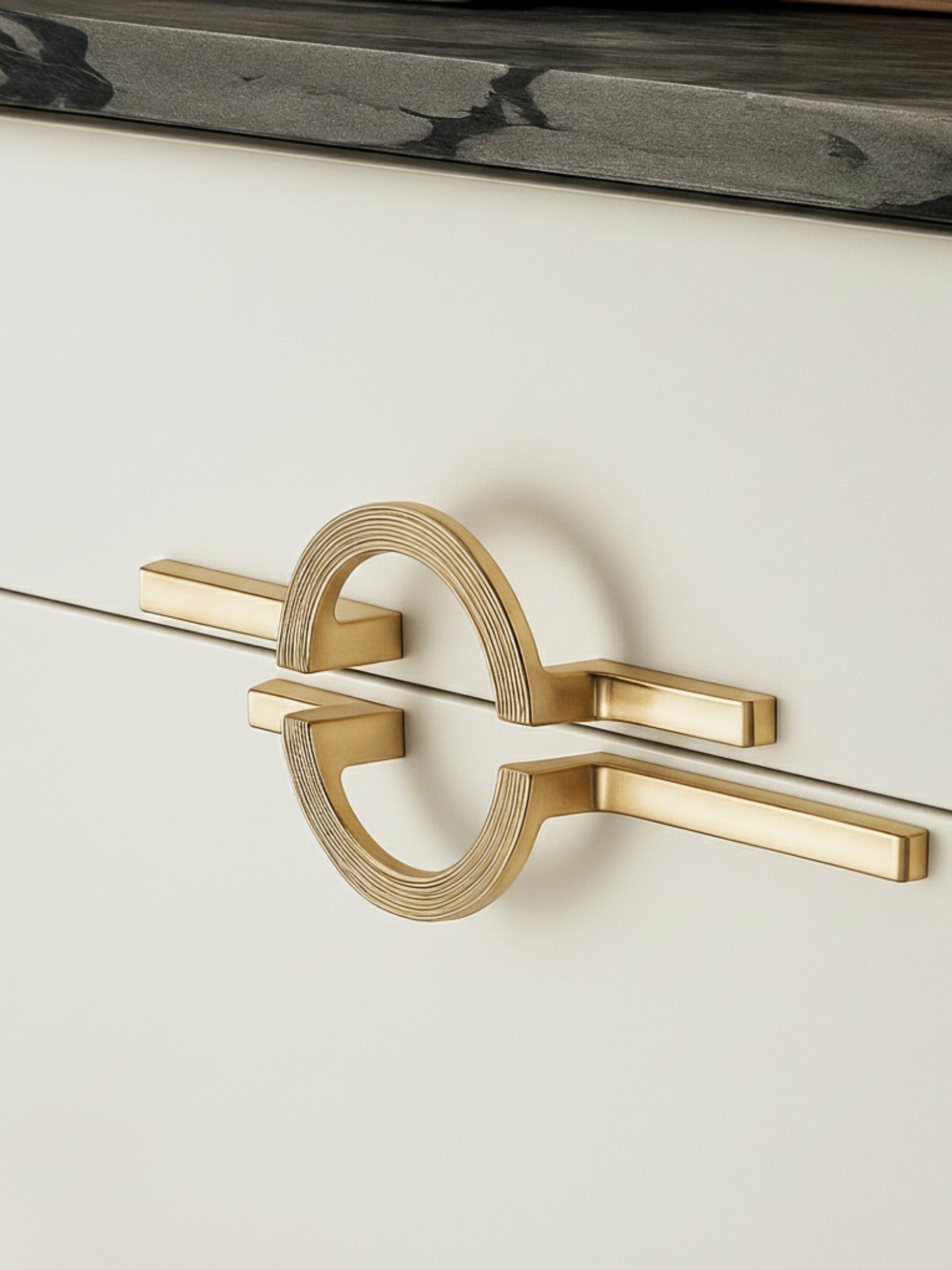 Two satin gold circle ring pulls installed horizontally on cream drawer fronts with marble countertop