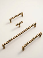 Set of antique brass bead handles on a light beige background