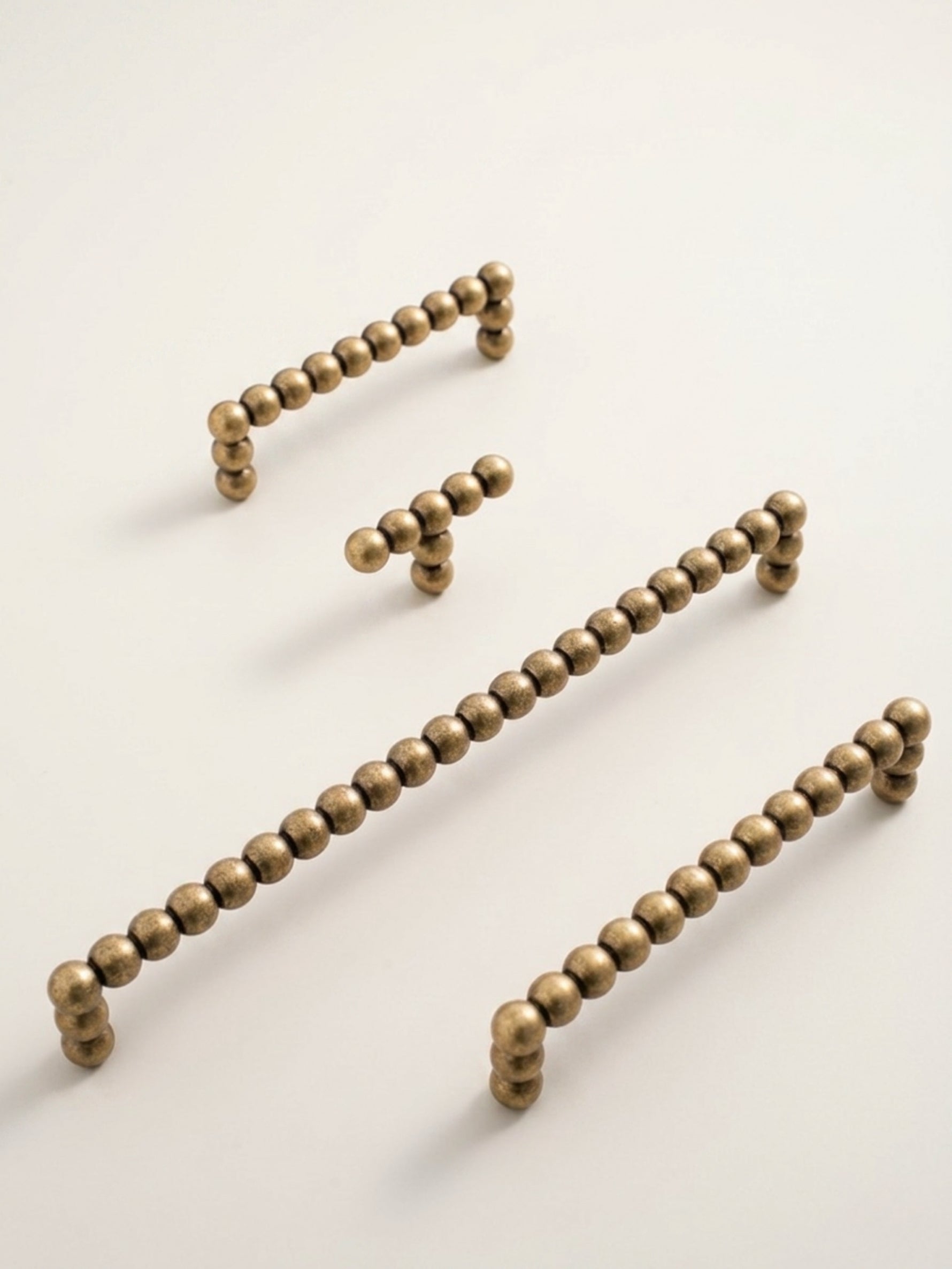 Set of antique brass bead handles on a light beige background