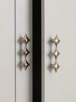 Two polished chrome star cabinet pulls on white wardrobe doors, vertical orientation