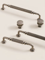 Antique silver reeded cabinet pulls and knob styled on cream surface, full set