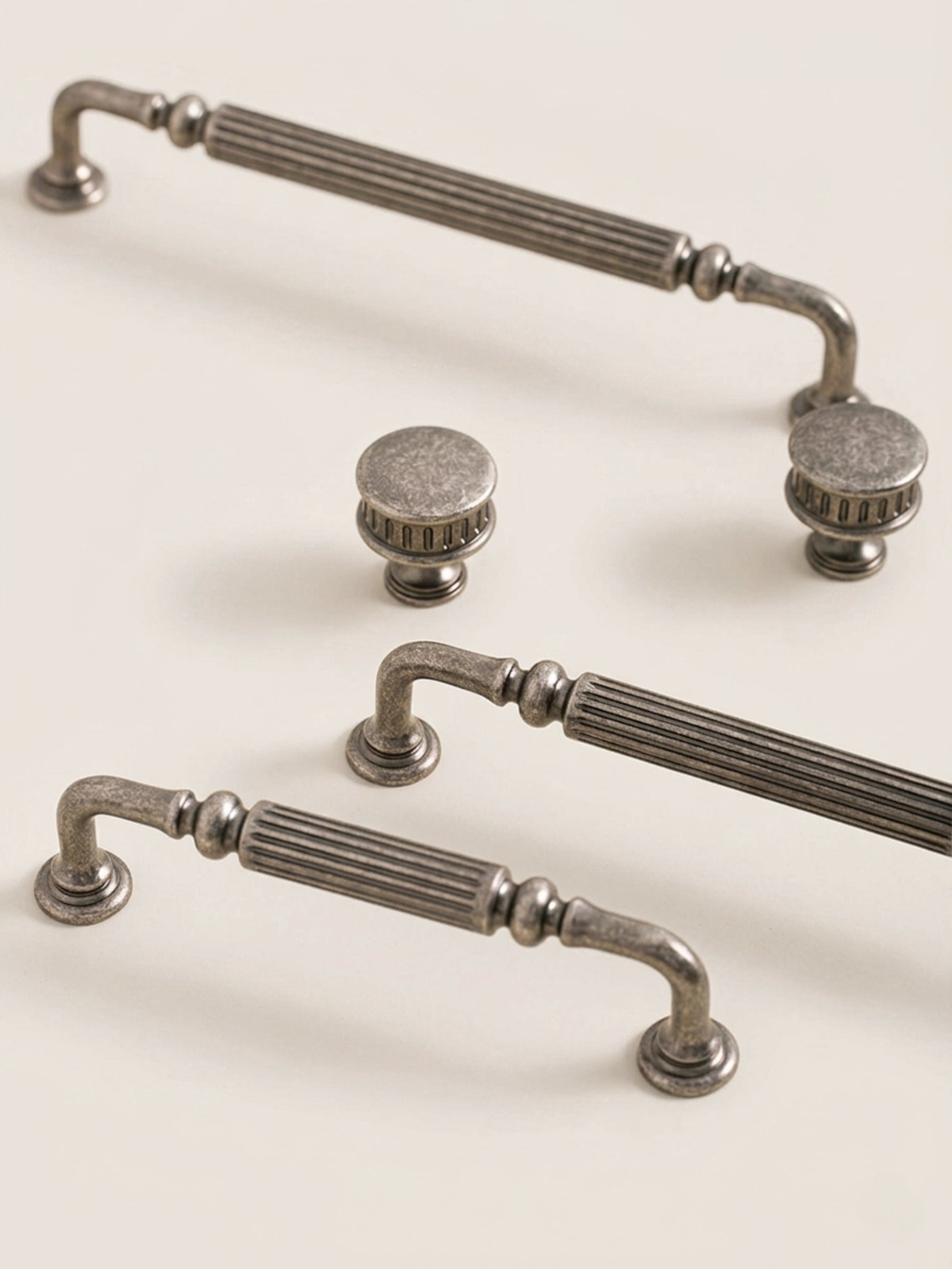 Antique silver reeded cabinet pulls and knob styled on cream surface, full set