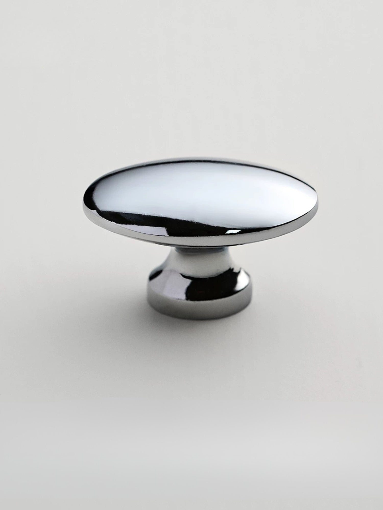Polished chrome oval cabinet knob on white background — pedestal base side view