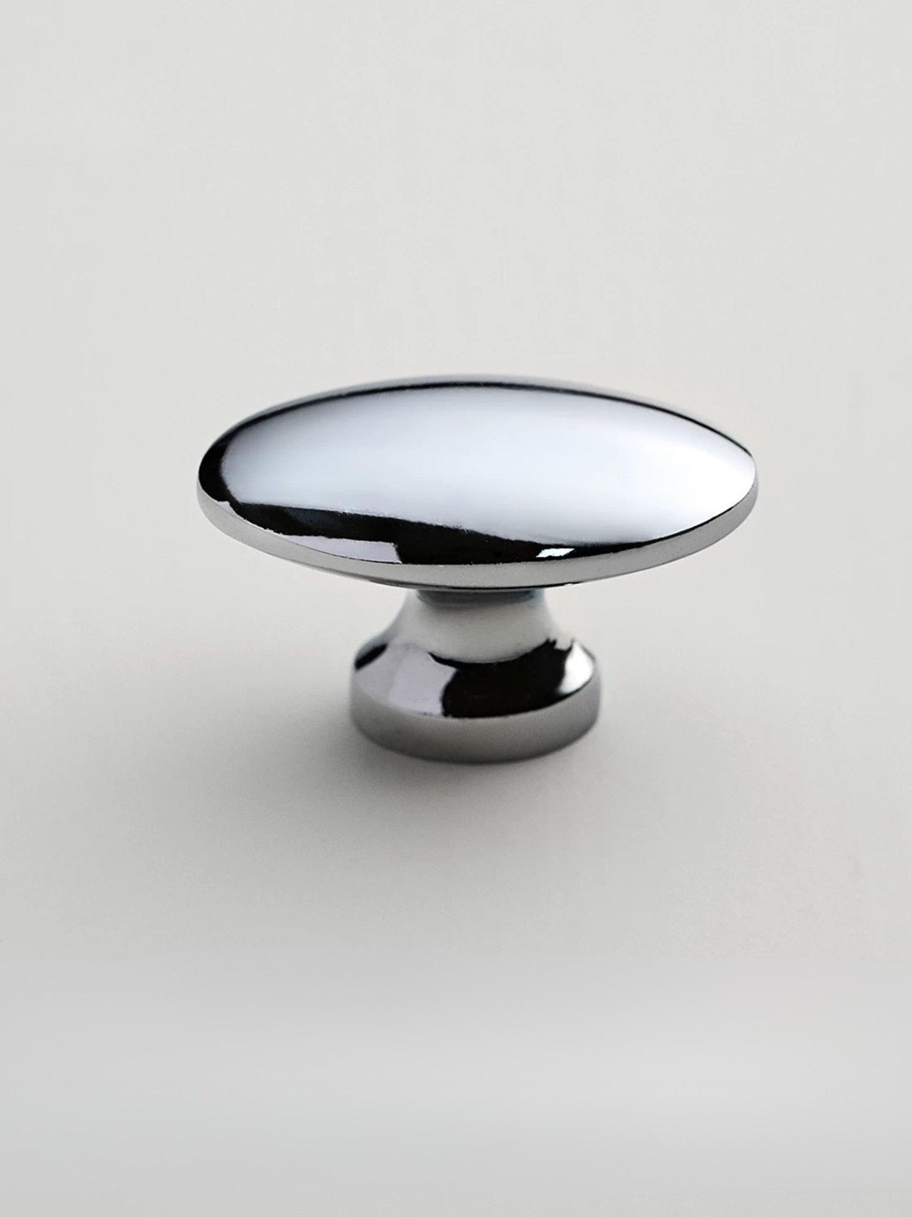 Polished chrome oval cabinet knob on white background — pedestal base side view