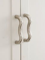 Two polished chrome wavy S-curve cabinet pulls on white wardrobe doors