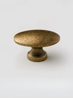 Antique brass oval cabinet knob on white background — pedestal base side view