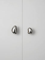 Two polished chrome pebble cabinet knobs on white wardrobe doors, front view