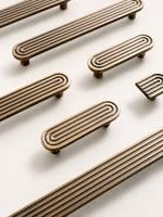 Flat lay of solid brass Art Deco arch pulls and matching arch knob in antique brass finish
