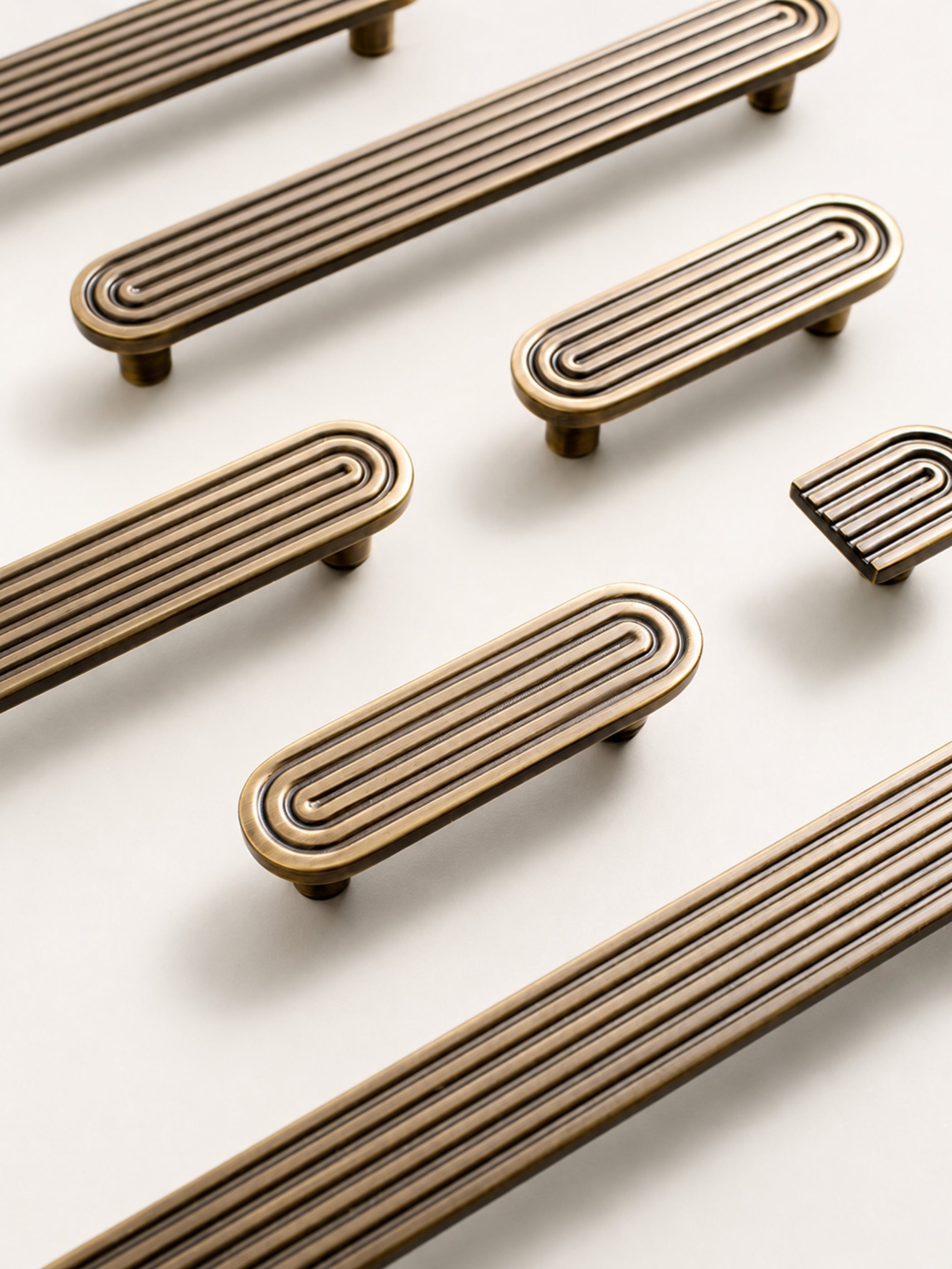 Flat lay of solid brass Art Deco arch pulls and matching arch knob in antique brass finish