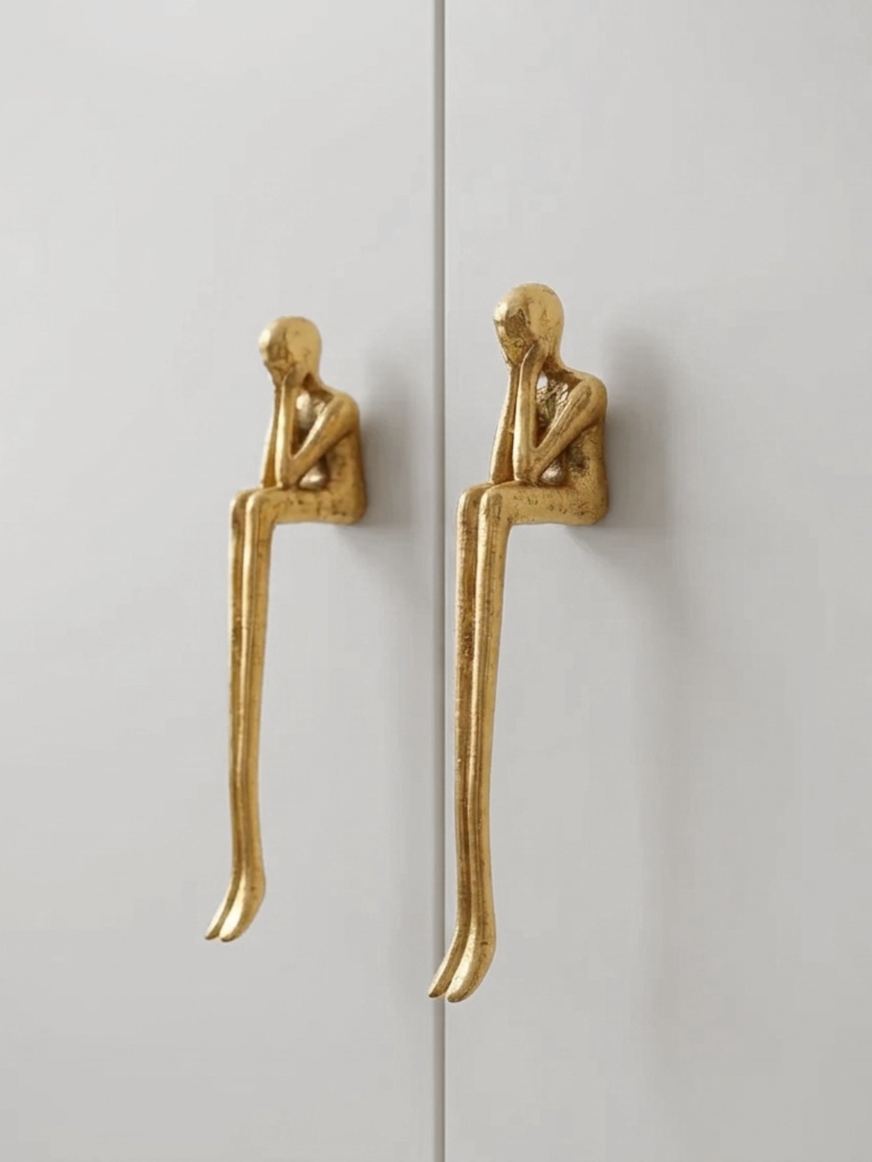 Gold thinker figure cabinet pulls on white wardrobe door