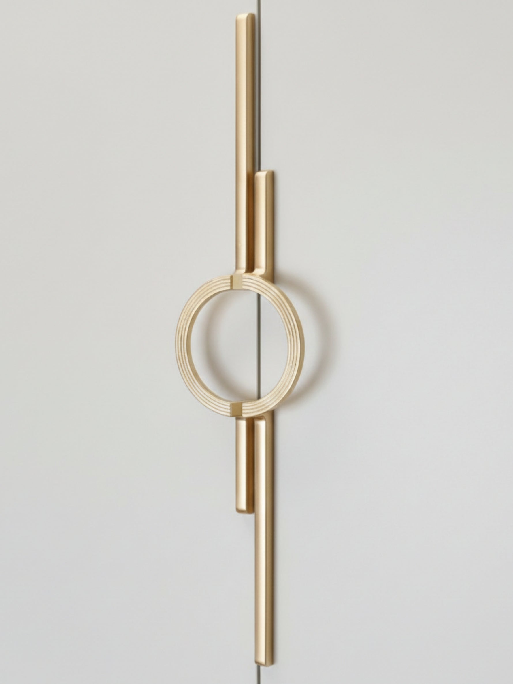 Satin gold circle ring cabinet pull mounted vertically on light grey wardrobe door