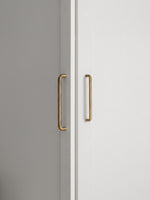 Two brushed brass handles on a white and gray cabinet