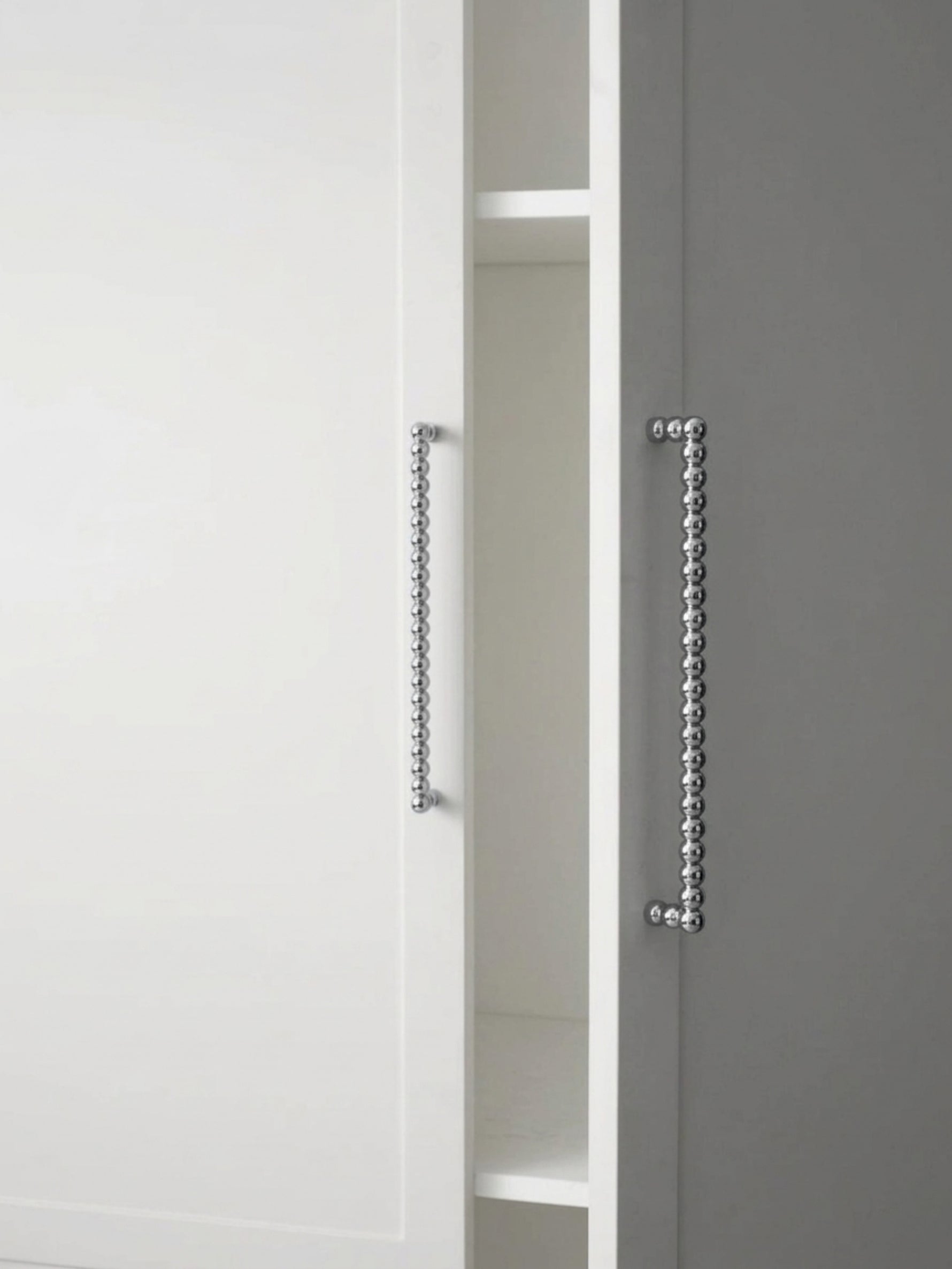 Close-up of polished chrome beaded ball pulls on white and grey cabinet doors