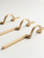 Three satin gold arch semi-circle drawer pulls on white background, multiple sizes