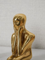Close-up of gold sculptural thinker figure pull — head and torso detail