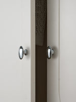 Two polished chrome oval knobs on white and dark cabinet doors