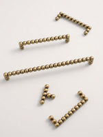 Set of antique brass beaded drawer pulls on a white background