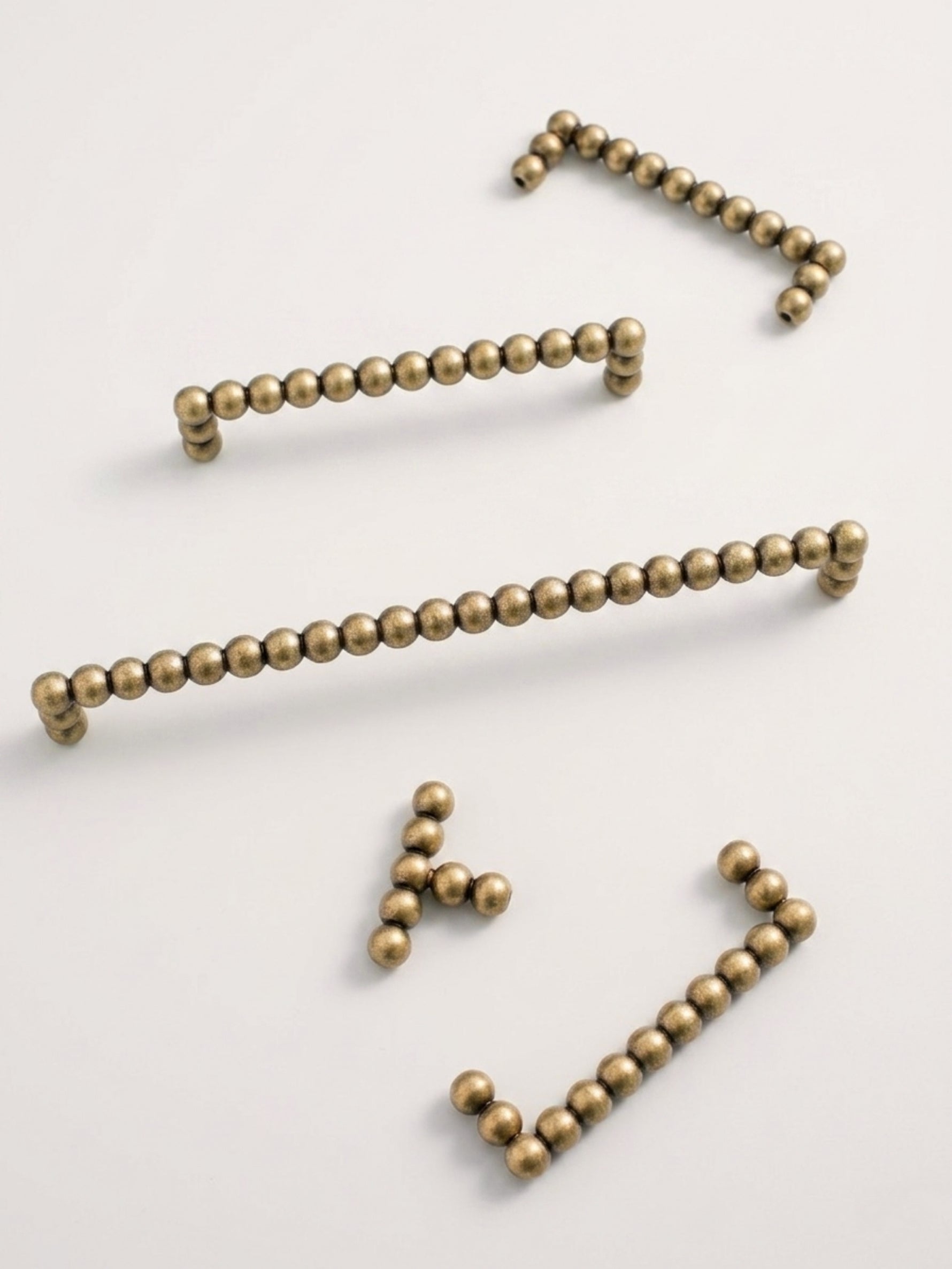Set of antique brass beaded drawer pulls on a white background