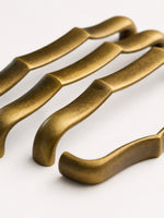 Close-up antique brass bamboo pull — wavy texture detail