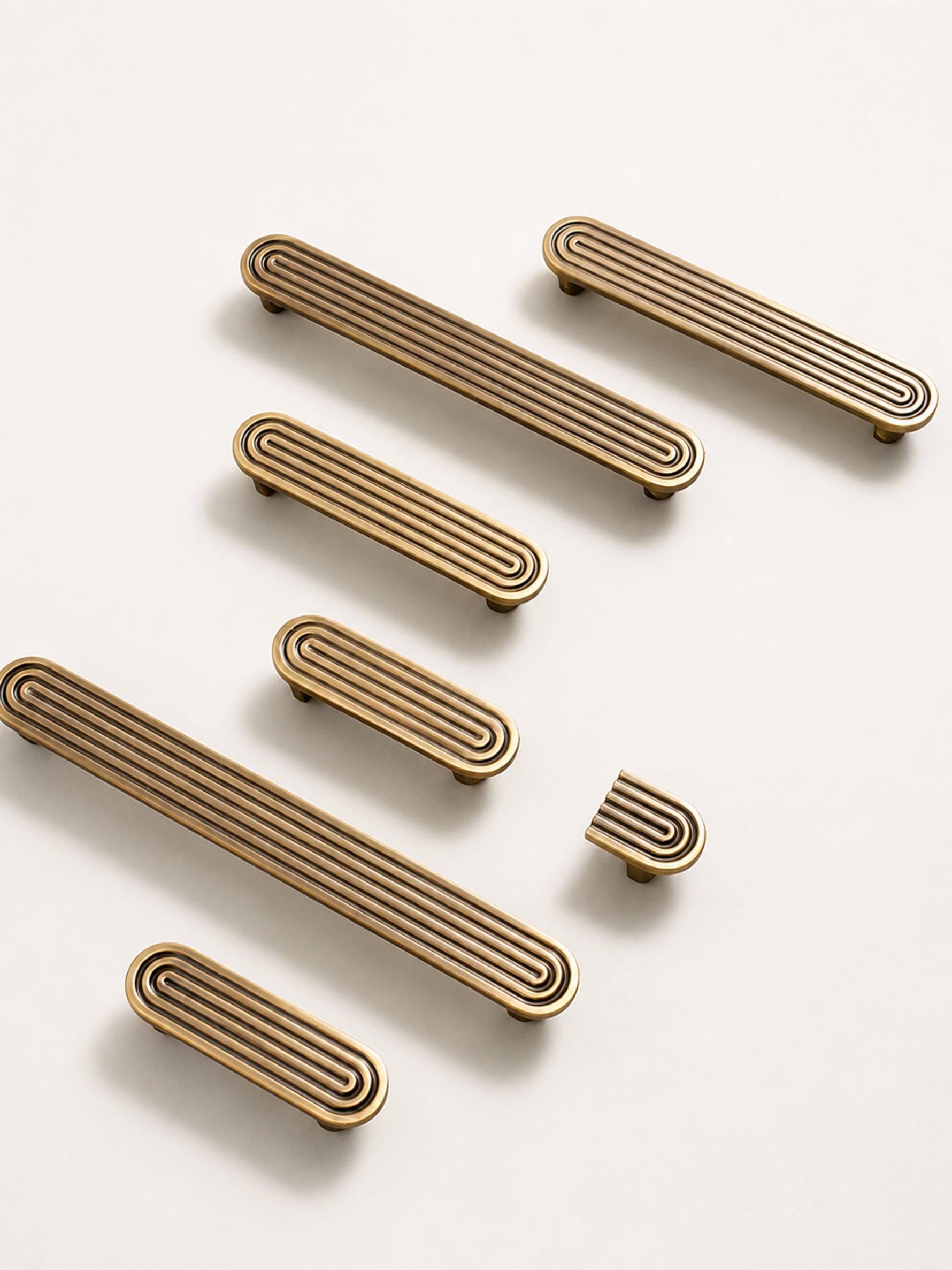 Antique brass solid brass Art Deco arch cabinet pulls in multiple sizes with concentric groove detail on cream background