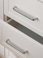 Polished chrome bar pulls on open cream Shaker drawer fronts