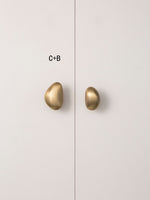 Mixed size C and B brushed brass pebble knobs on cabinet