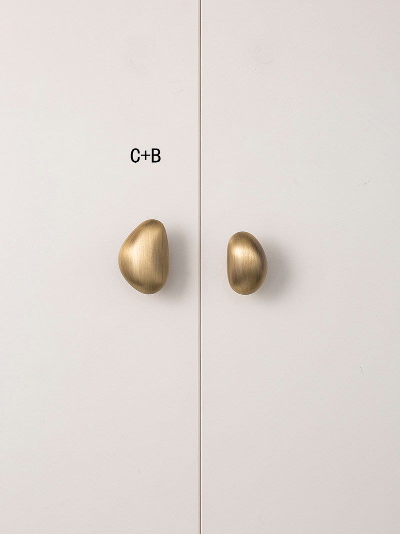 Mixed size C and B brushed brass pebble knobs on cabinet