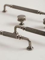 Antique silver reeded cabinet pulls and knob, close-up angled view