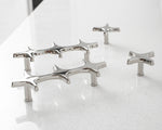 Five polished chrome star cross pulls and knobs arranged on white speckled countertop