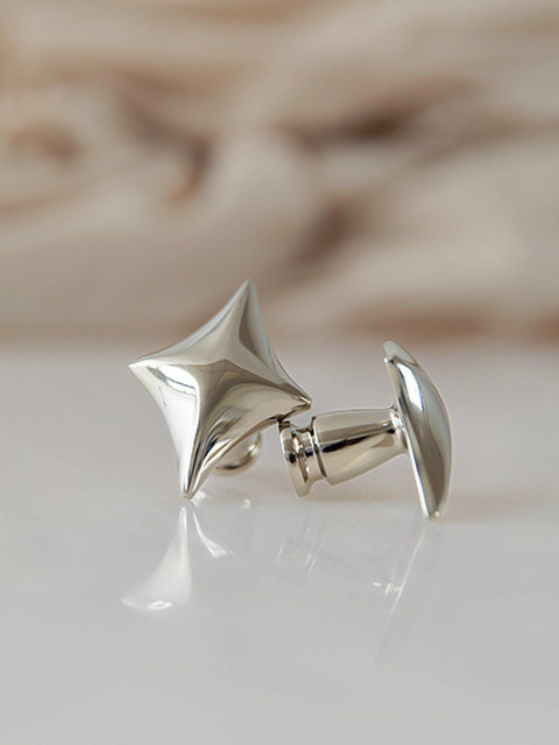 Polished chrome star cabinet knob close-up on marble surface, side view
