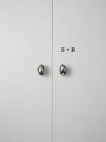 Polished chrome pebble knobs on white cabinet doors labeled size B plus B comparison