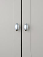 Two polished chrome oval knobs on grey cabinet doors, front view