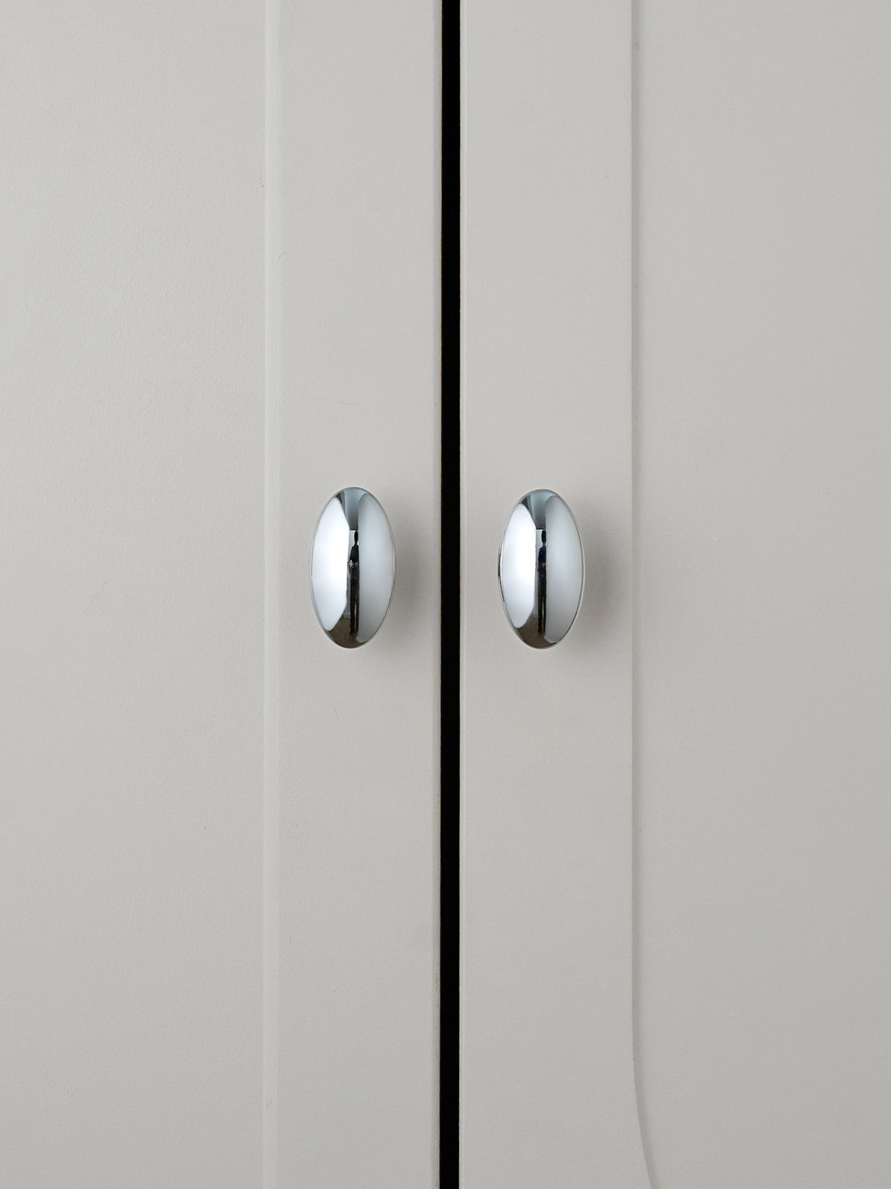 Two polished chrome oval knobs on grey cabinet doors, front view
