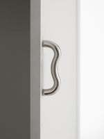 Close-up polished chrome wavy S-curve pull mounted vertically on white cabinet door