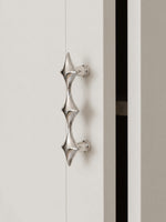 Single polished chrome star cabinet pull on white door, close-up side view