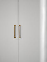 Close-up of a light gray cabinet with brushed brass handles on a white background