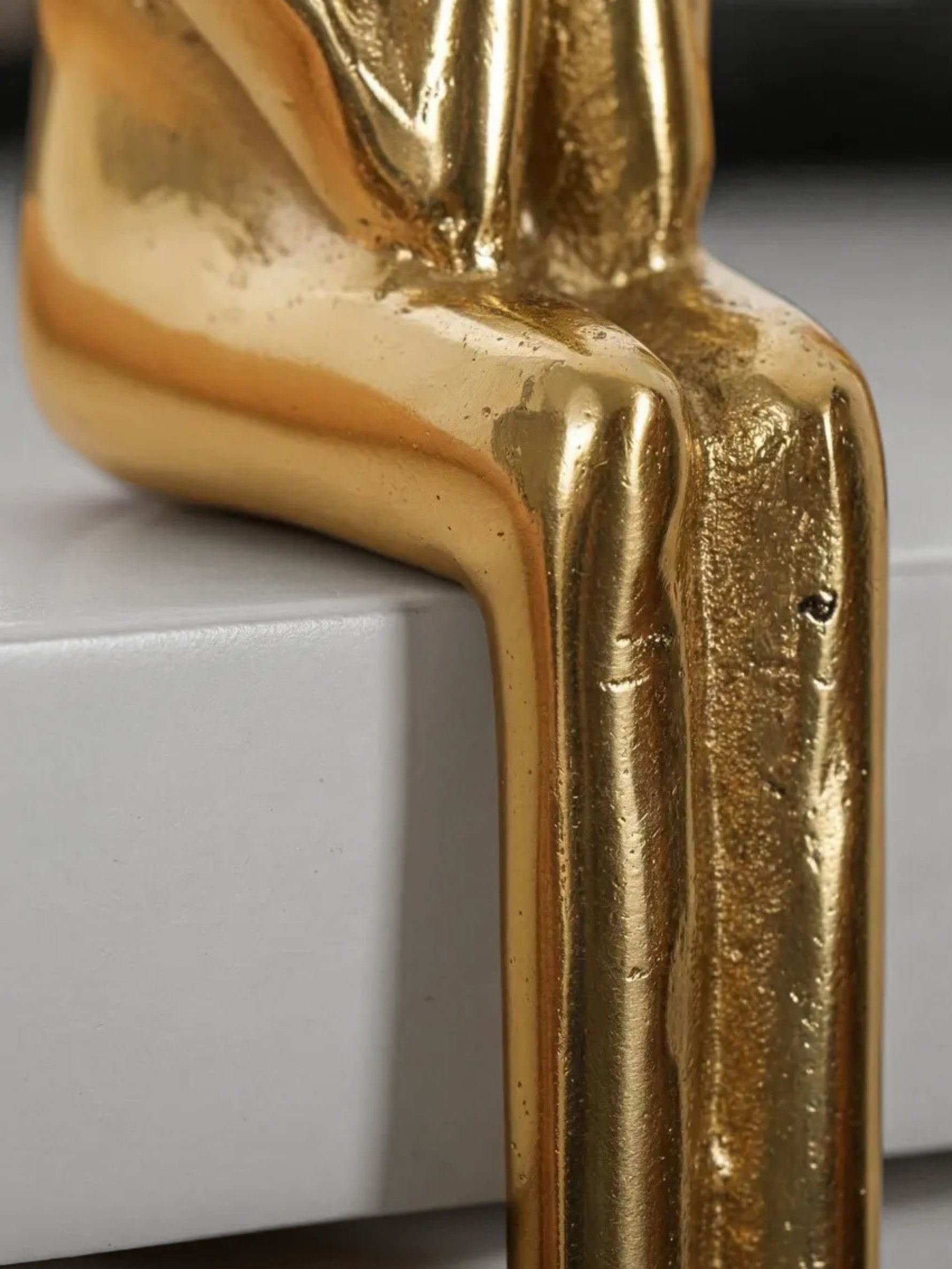 Gold thinker figure pull legs detail on cabinet edge