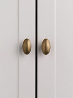 Two antique brass oval knobs on grey cabinet doors, front view