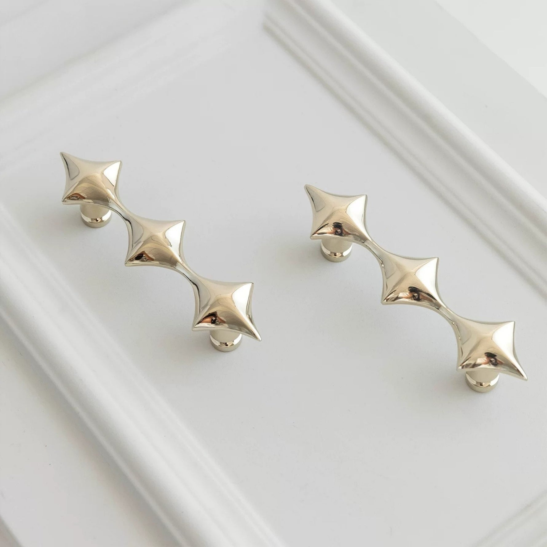 Pair of chrome star-shaped earrings on a white background