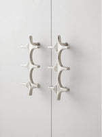 Close-up polished chrome star cross pulls on white cabinet doors with visible screws