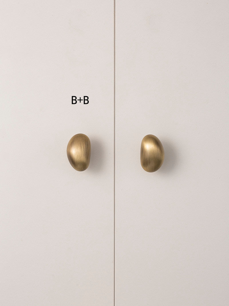 Size B brushed brass pebble knobs on white cabinet door