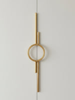 Single satin gold circle ring door pull on light grey wardrobe door, front view