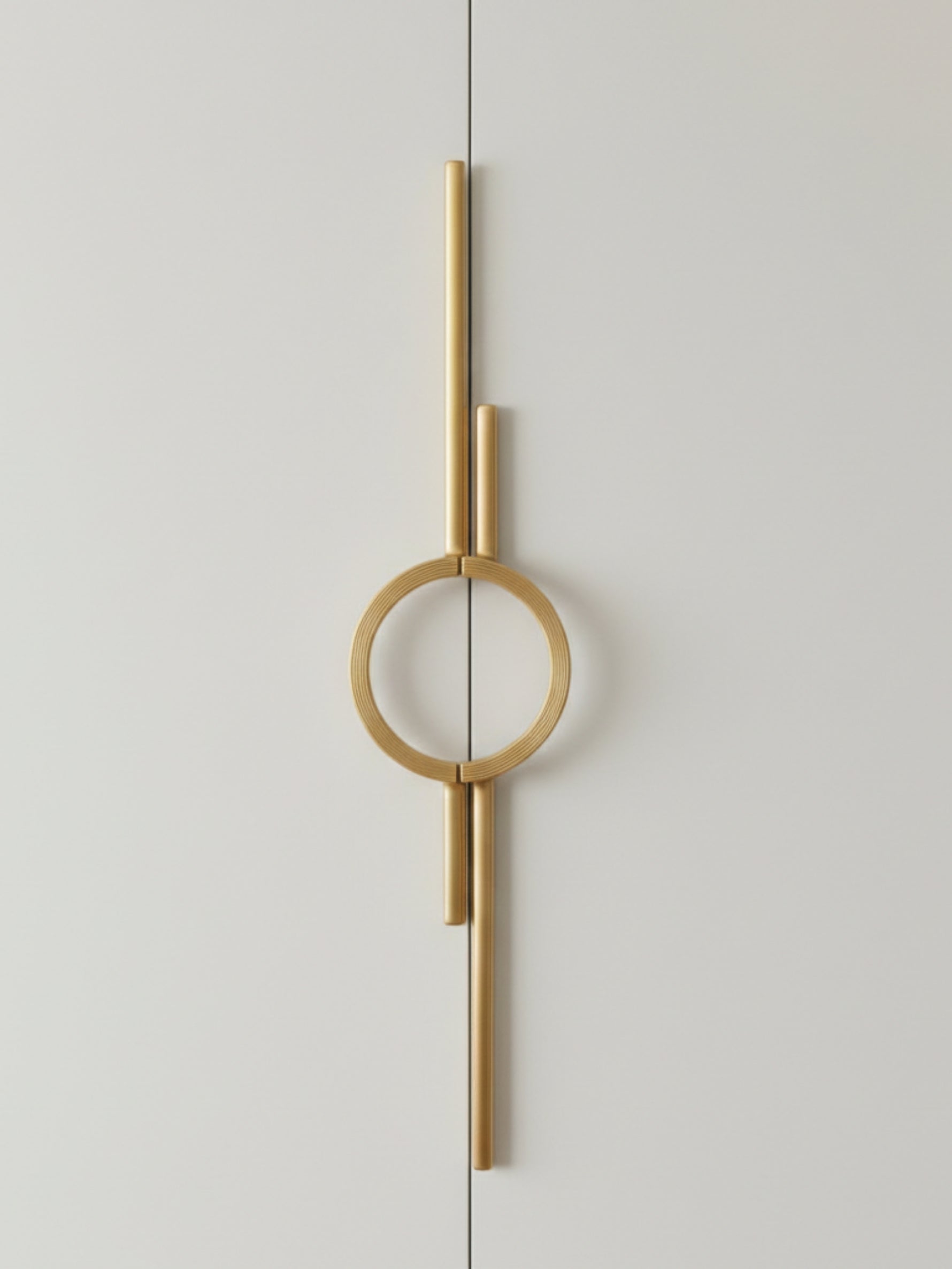 Single satin gold circle ring door pull on light grey wardrobe door, front view