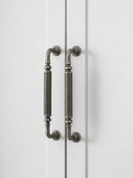 Two antique silver reeded cabinet pulls on white wardrobe doors, vertical
