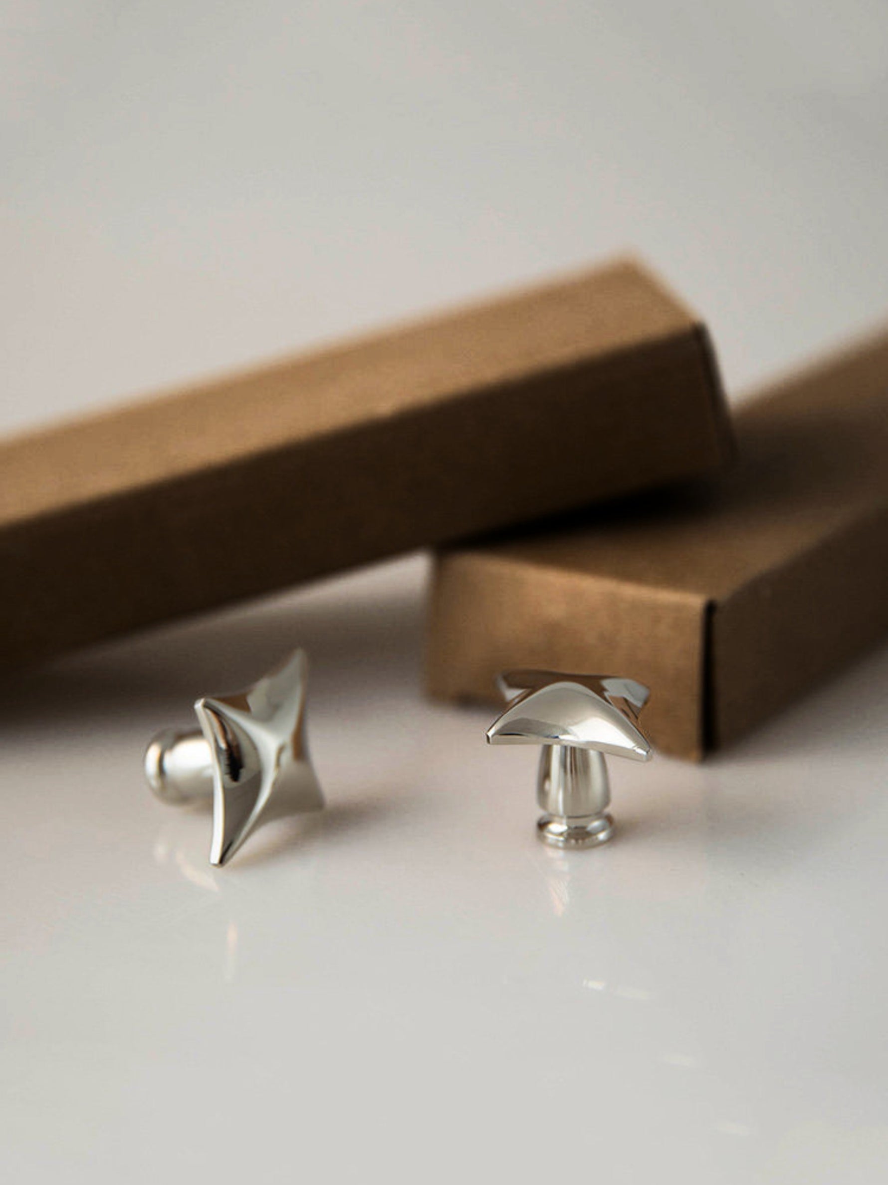 Two polished chrome star knobs with kraft paper packaging boxes