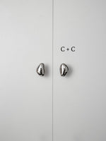 Polished chrome pebble knobs on white cabinet doors labeled size C plus C comparison