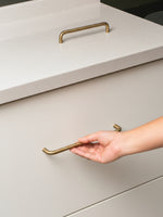 Hand opening a light gray drawer with brushed brass handle