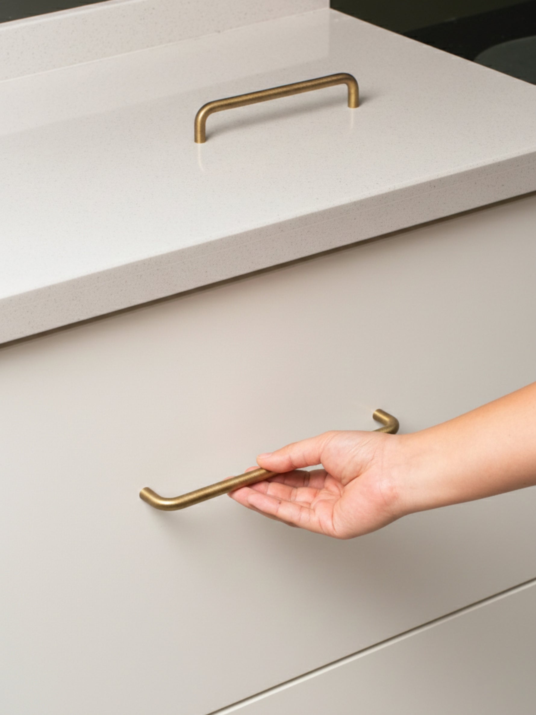 Hand opening a light gray drawer with brushed brass handle